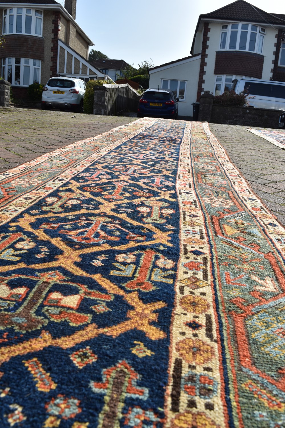 An extra long antique hand-knotted wool runner rug with a dark blue central panel of geometric diamond medallions and terracotta patterned borders. View VIII