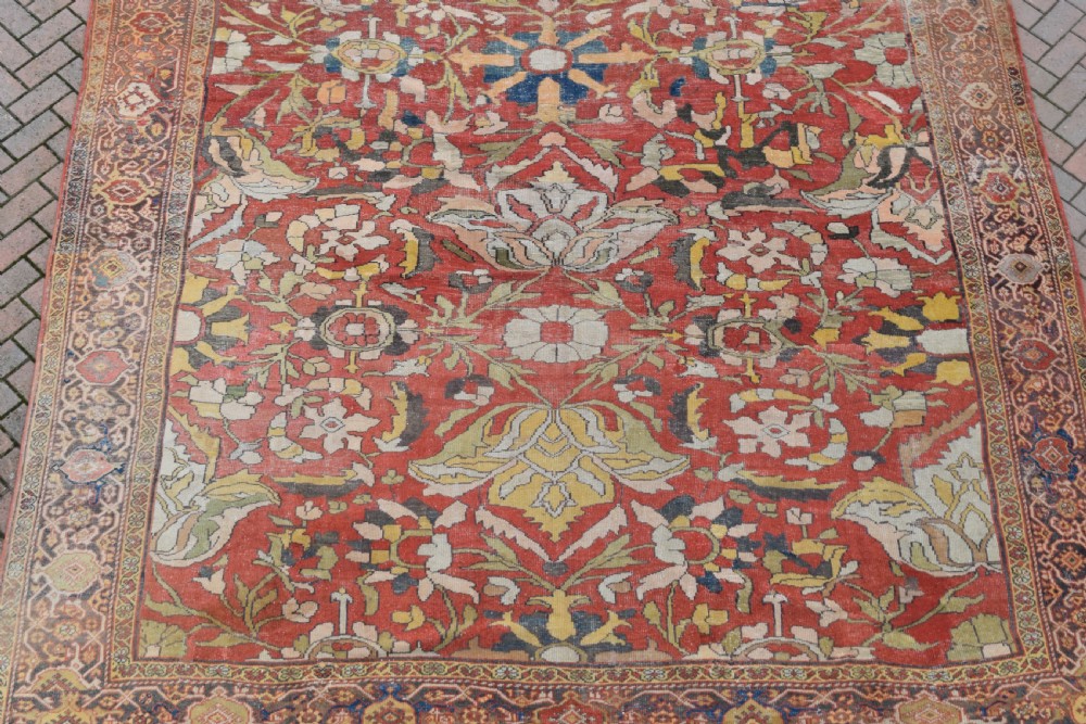 A large antique Persian Sultanabad hand-knotted wool carpet with large botanical palmettes on a terracotta field enclosed by multi-band borders. View II