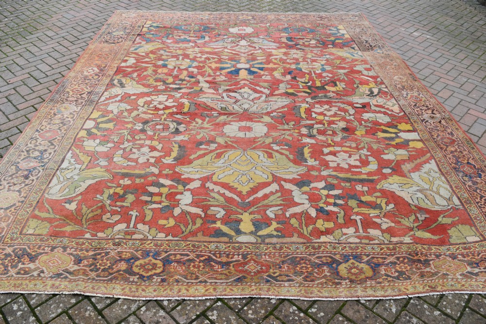 A large antique Persian Sultanabad hand-knotted wool carpet with large botanical palmettes on a terracotta field enclosed by multi-band borders. View V