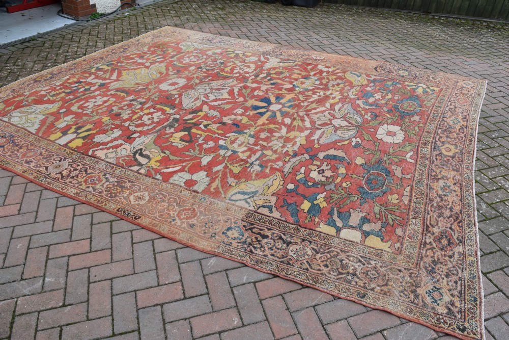 A large antique Persian Sultanabad hand-knotted wool carpet with large botanical palmettes on a terracotta field enclosed by multi-band borders. View X