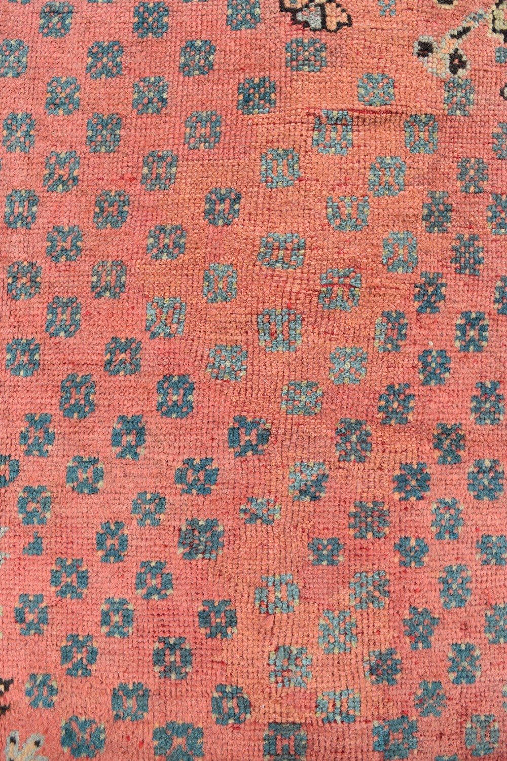 A large square hand-knotted wool Ushak carpet featuring a coral red field, a central teal medallion, cream corner spandrels, and patterned borders. View VI