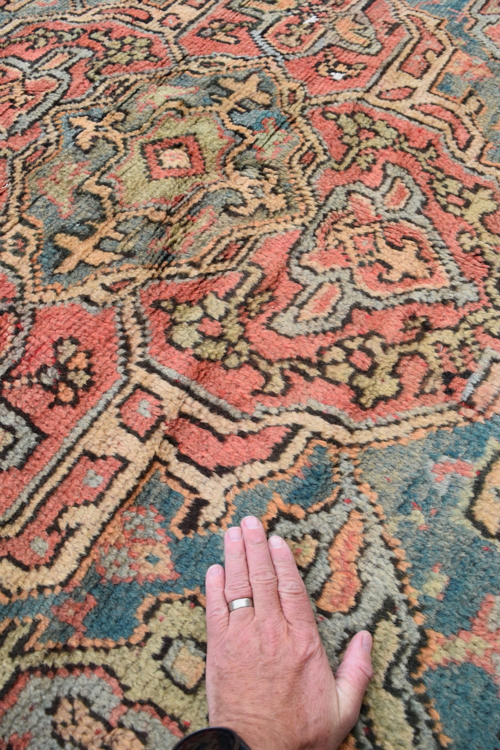 A large square hand-knotted wool Ushak carpet featuring a coral red field, a central teal medallion, cream corner spandrels, and patterned borders. View VIII
