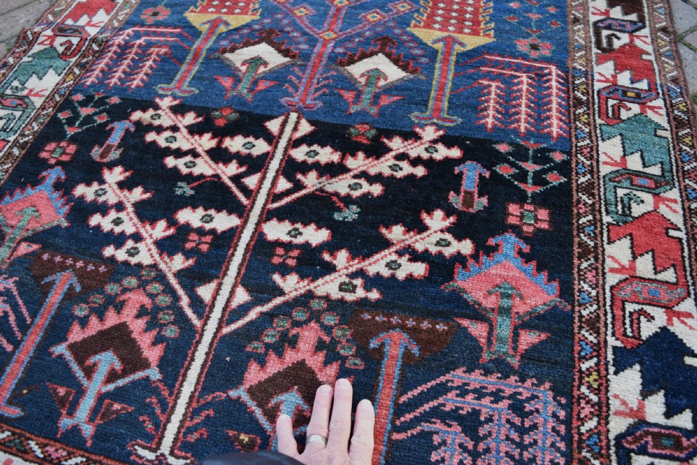 A long antique Persian Bakhtiari runner rug featuring stylised tree motifs in red, blue, and pink on a dark navy ground with a geometric border. View III