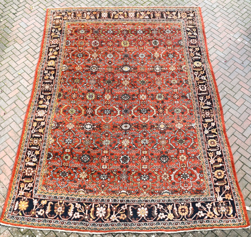 A large rectangular antique Mahal carpet featuring an all-over intricate floral lattice pattern in terracotta red and cream framed by a wide navy border.