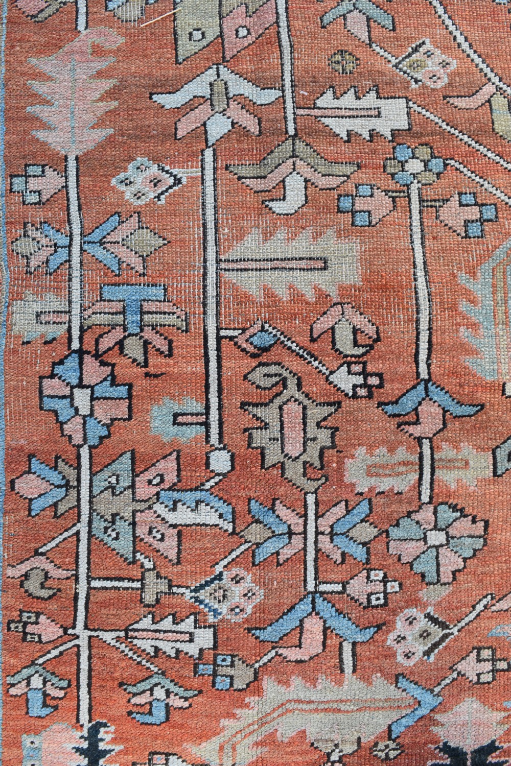 A large hand-knotted Persian Heriz carpet featuring a bold geometric central medallion on a terracotta field with navy blue and cream borders. View II