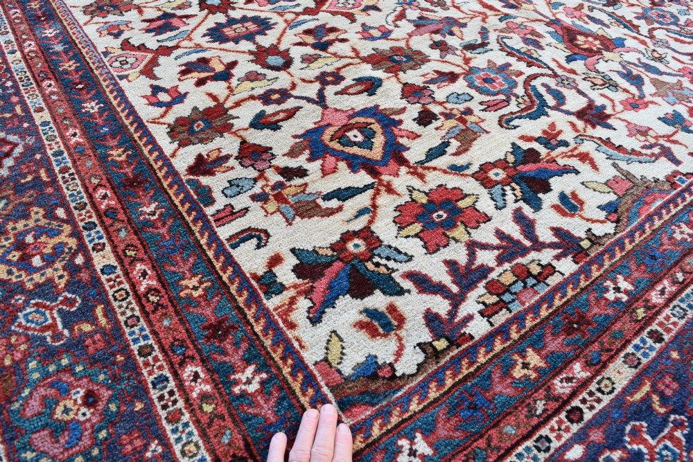 A large hand-knotted Persian Mahal carpet featuring an cream field with red, blue, and terracotta floral palmettes enclosed by a multi-band navy and red border. View II