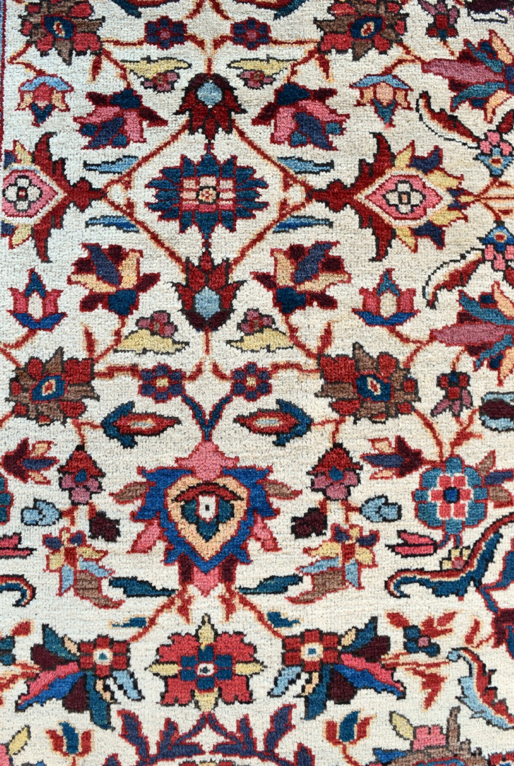A large hand-knotted Persian Mahal carpet featuring an cream field with red, blue, and terracotta floral palmettes enclosed by a multi-band navy and red border. View III