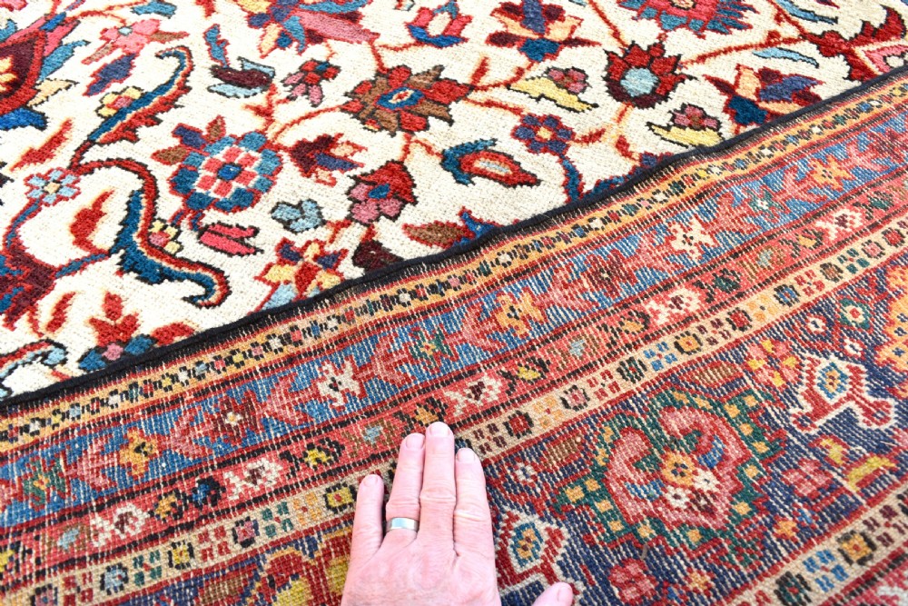 A large hand-knotted Persian Mahal carpet featuring an cream field with red, blue, and terracotta floral palmettes enclosed by a multi-band navy and red border. View IV