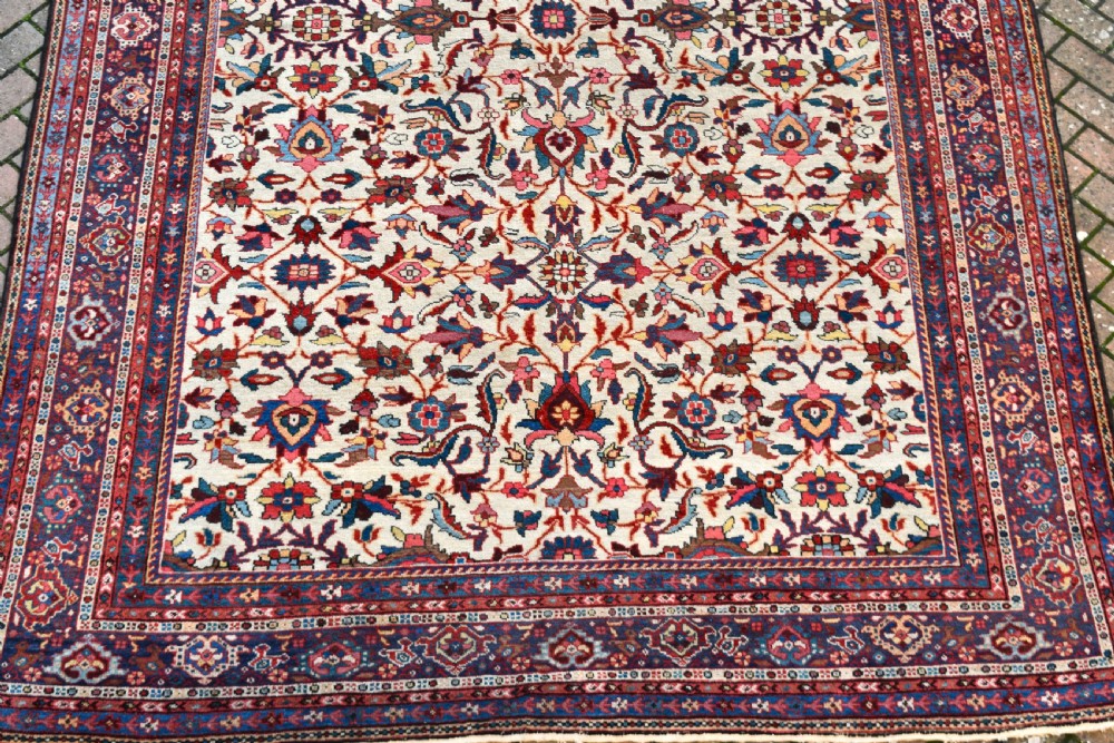 A large hand-knotted Persian Mahal carpet featuring an cream field with red, blue, and terracotta floral palmettes enclosed by a multi-band navy and red border. View VI