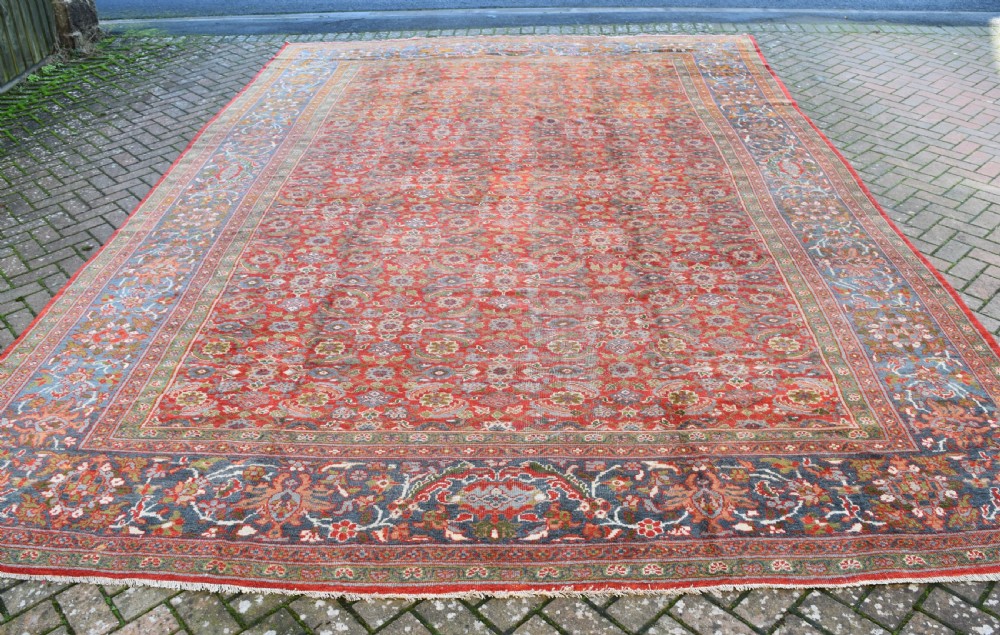 A large rectangular hand-knotted Sultanabad rug featuring an all-over floral lattice pattern on a terracotta red field with a slate blue palmette border. View II