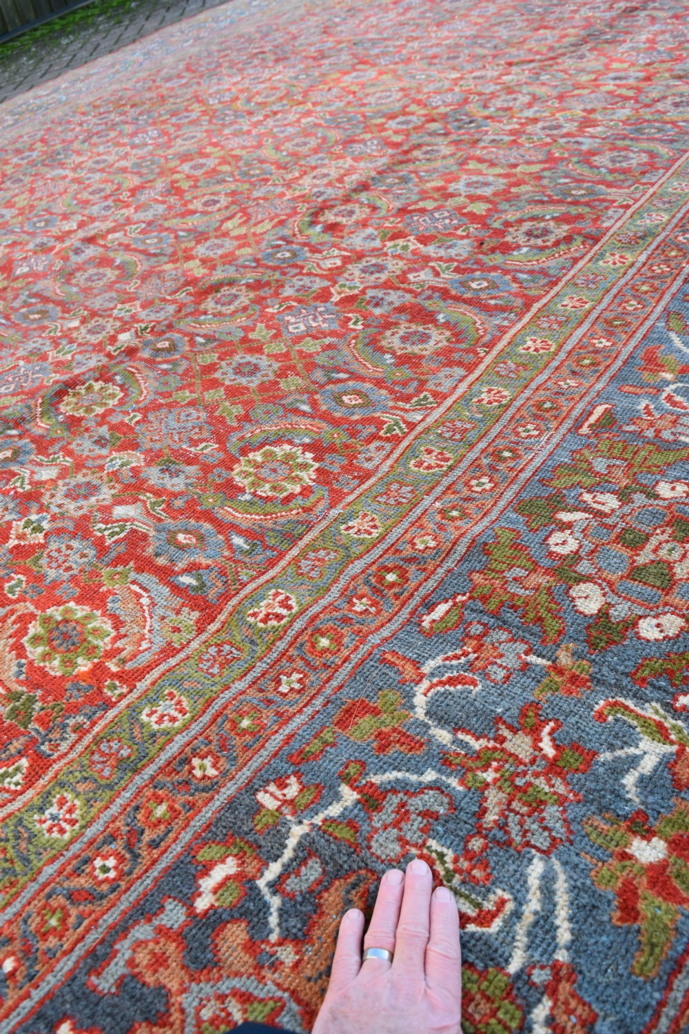 A large rectangular hand-knotted Sultanabad rug featuring an all-over floral lattice pattern on a terracotta red field with a slate blue palmette border. View IV