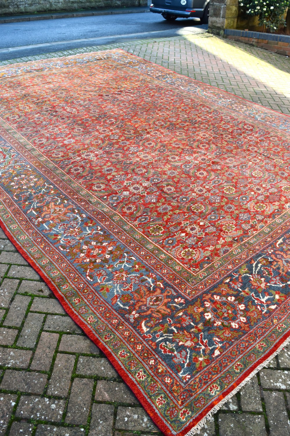 A large rectangular hand-knotted Sultanabad rug featuring an all-over floral lattice pattern on a terracotta red field with a slate blue palmette border. View V