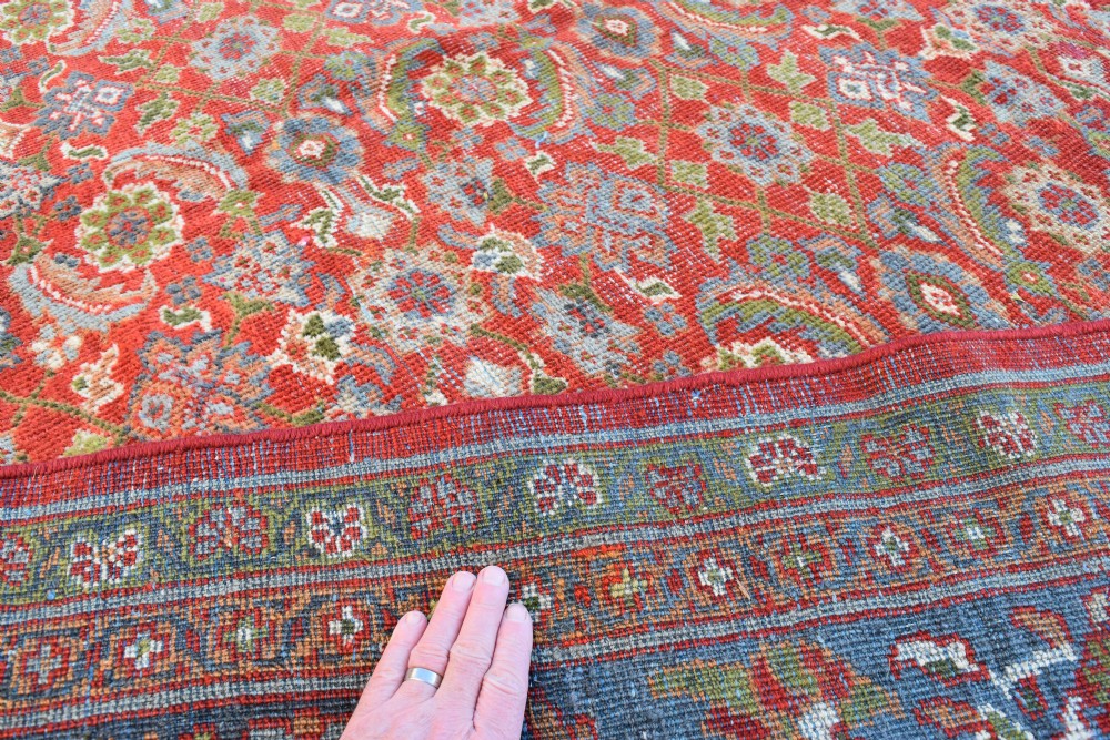 A large rectangular hand-knotted Sultanabad rug featuring an all-over floral lattice pattern on a terracotta red field with a slate blue palmette border. View VI