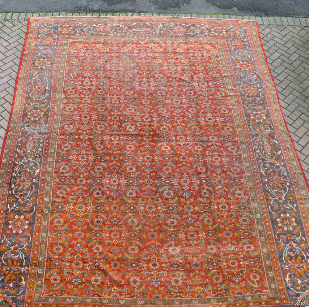 A large rectangular hand-knotted Sultanabad rug featuring an all-over floral lattice pattern on a terracotta red field with a slate blue palmette border. View X