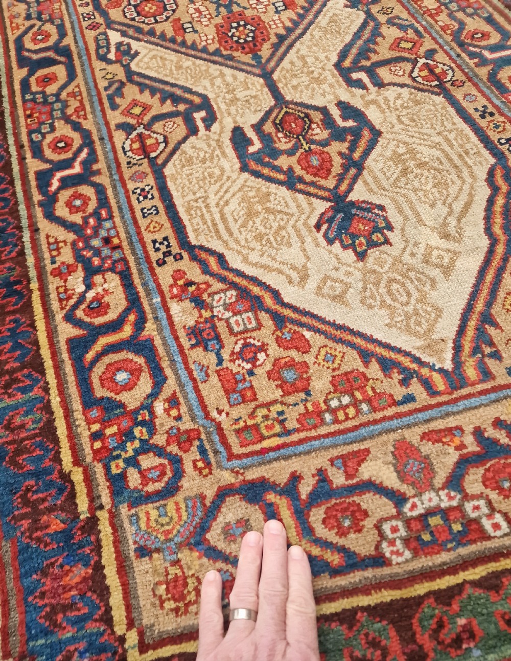 A long, narrow antique Persian Serab wool carpet runner featuring geometric diamond medallions on a camel-coloured field with red and navy patterned borders. View IV