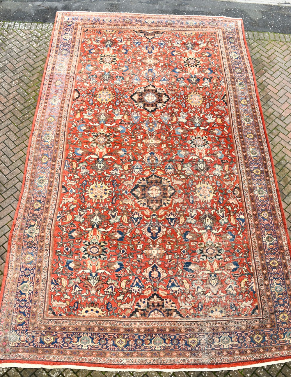 An oversized hand-knotted antique Persian Mahal carpet featuring an intricate terracotta red field and complex dark navy blue floral borders.
