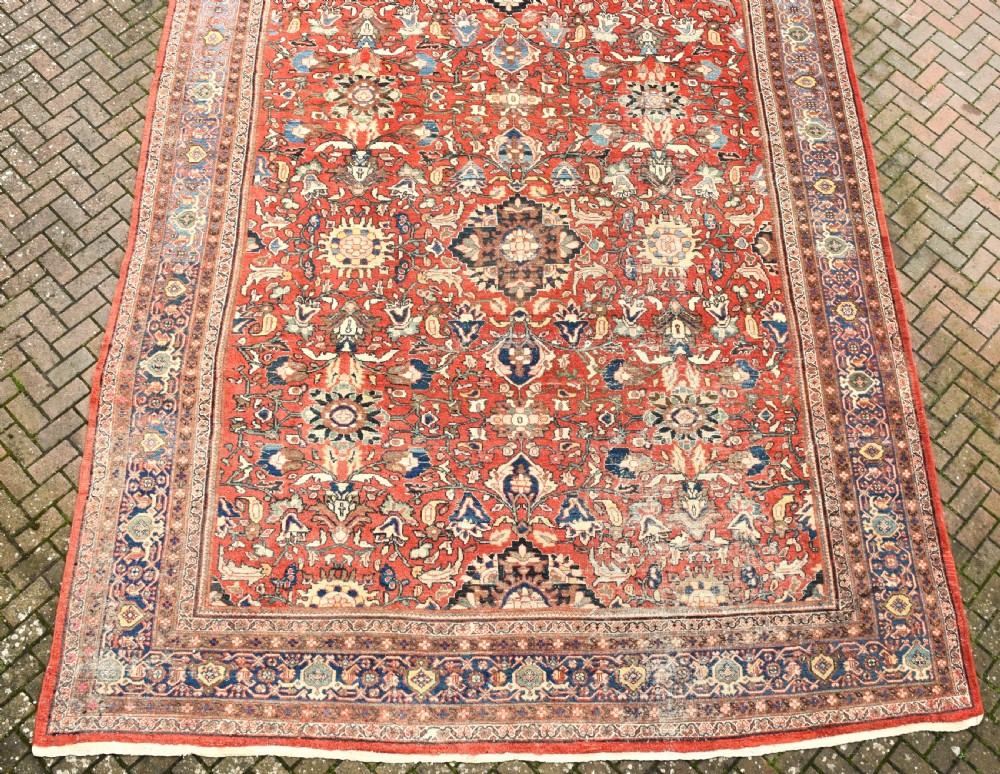 An oversized hand-knotted antique Persian Mahal carpet featuring an intricate terracotta red field and complex dark navy blue floral borders. View II