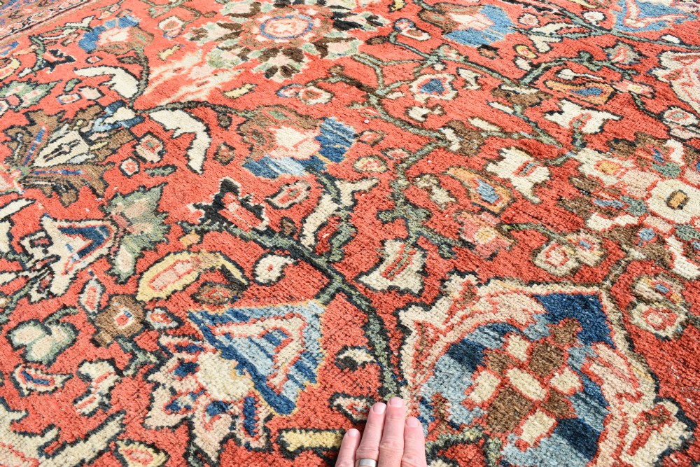 An oversized hand-knotted antique Persian Mahal carpet featuring an intricate terracotta red field and complex dark navy blue floral borders. View VI