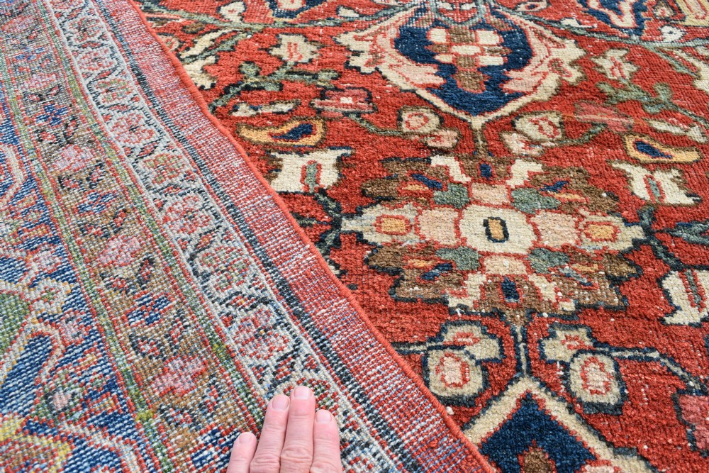 An oversized hand-knotted antique Persian Mahal carpet featuring an intricate terracotta red field and complex dark navy blue floral borders. View IX