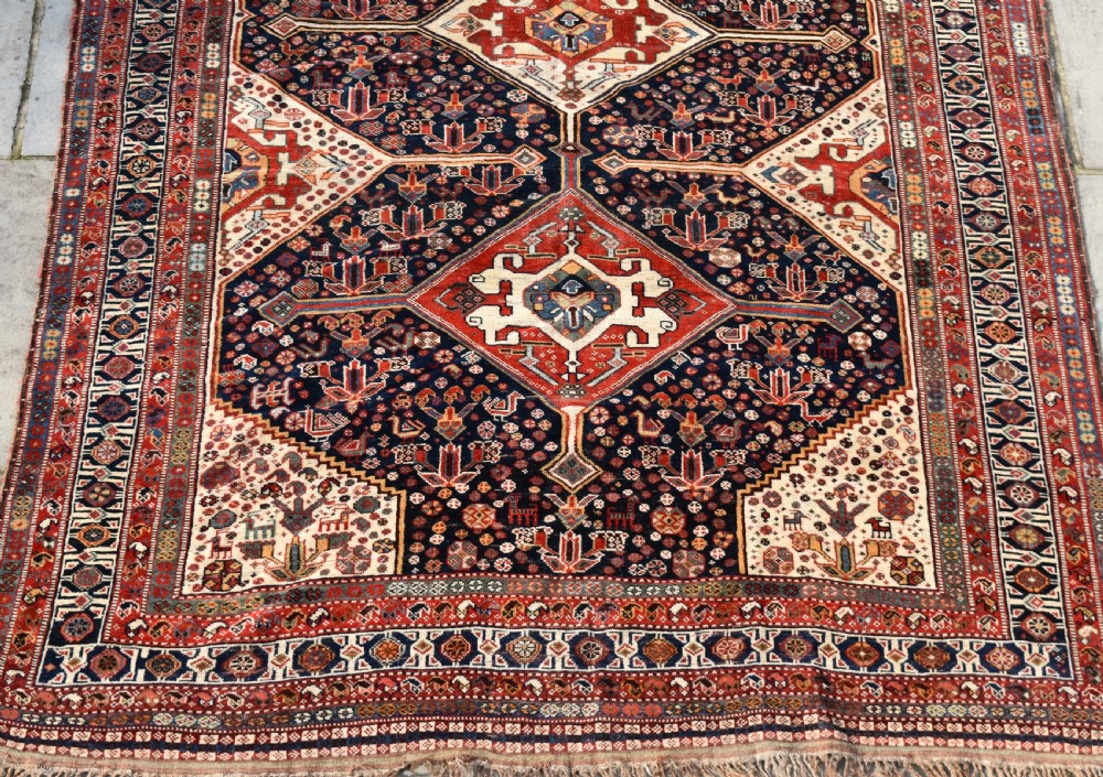 An antique hand-knotted Qashqai wool carpet featuring three central diamond medallions on a dark navy field surrounded by geometric borders. View II