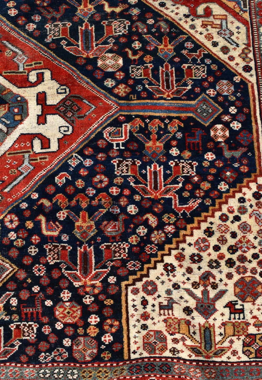 An antique hand-knotted Qashqai wool carpet featuring three central diamond medallions on a dark navy field surrounded by geometric borders. View V