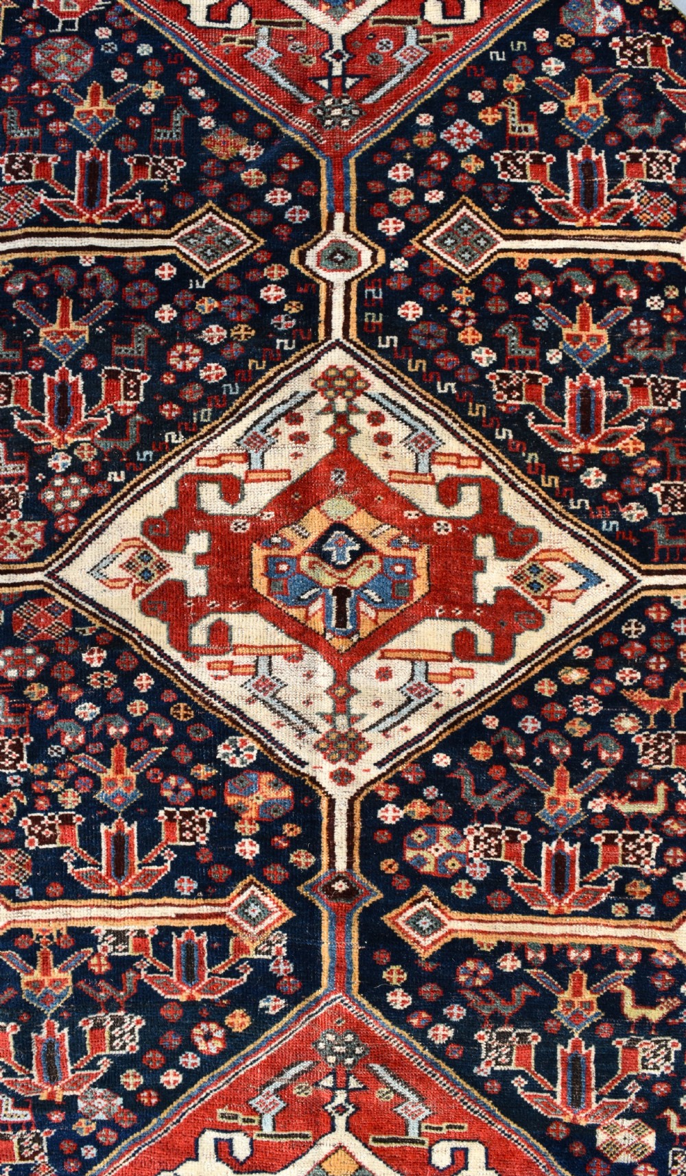 An antique hand-knotted Qashqai wool carpet featuring three central diamond medallions on a dark navy field surrounded by geometric borders. View VI