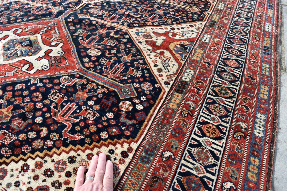 An antique hand-knotted Qashqai wool carpet featuring three central diamond medallions on a dark navy field surrounded by geometric borders. View VII