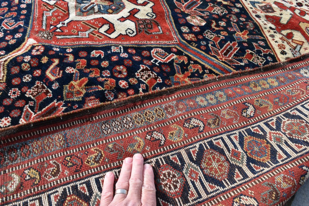 An antique hand-knotted Qashqai wool carpet featuring three central diamond medallions on a dark navy field surrounded by geometric borders. View VIII