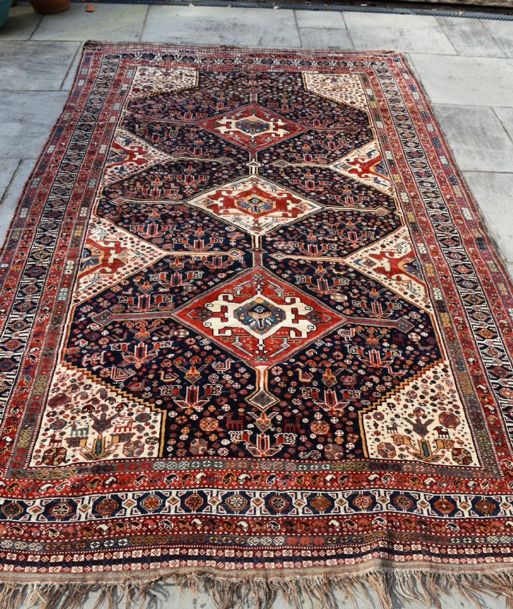 An antique hand-knotted Qashqai wool carpet featuring three central diamond medallions on a dark navy field surrounded by geometric borders. View IX