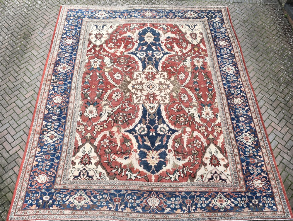 Large antique Ziegler Mahal wool carpet featuring a terracotta field with a central navy blue medallion and ornate floral borders.