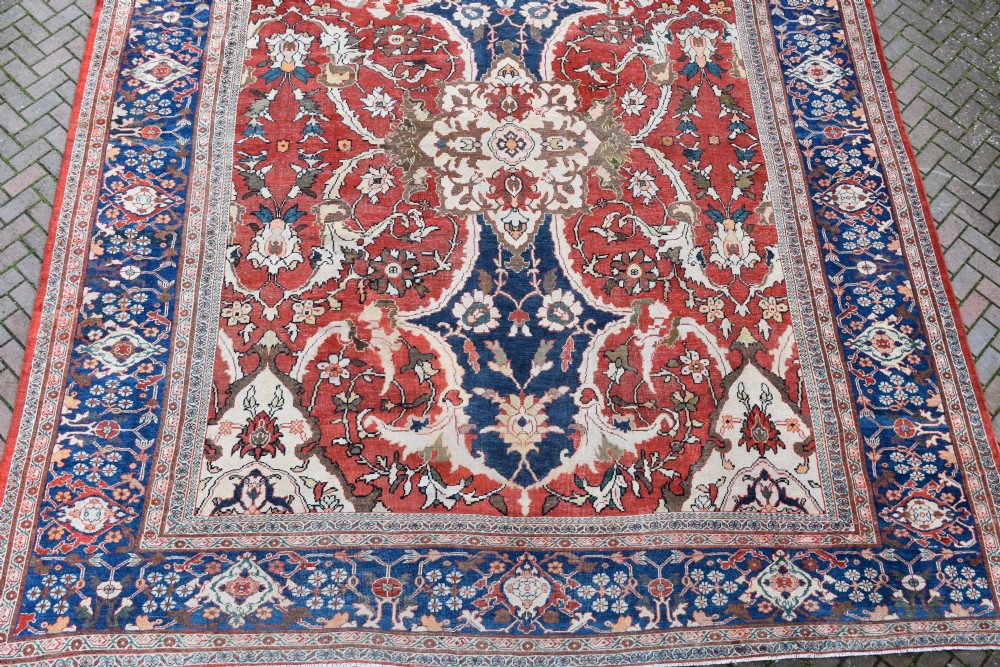 Large antique Ziegler Mahal wool carpet featuring a terracotta field with a central navy blue medallion and ornate floral borders. View III