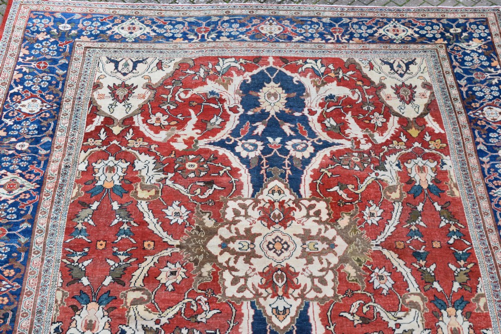 Large antique Ziegler Mahal wool carpet featuring a terracotta field with a central navy blue medallion and ornate floral borders. View VI