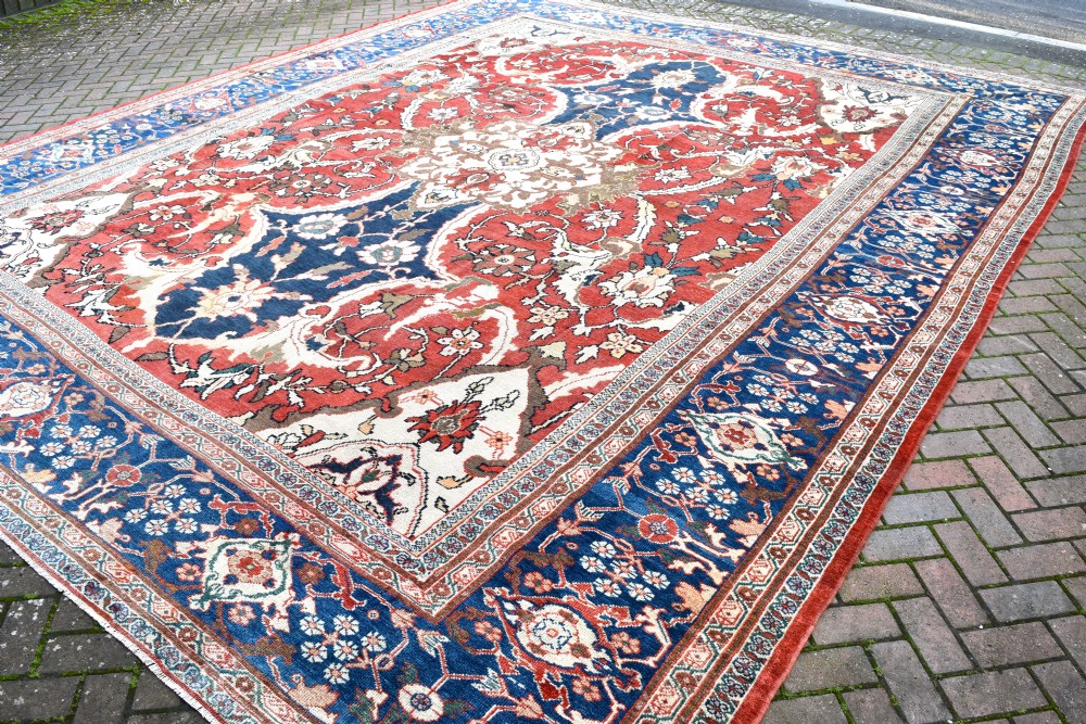 Large antique Ziegler Mahal wool carpet featuring a terracotta field with a central navy blue medallion and ornate floral borders. View VIII