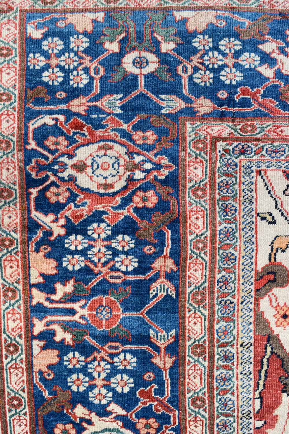 Large antique Ziegler Mahal wool carpet featuring a terracotta field with a central navy blue medallion and ornate floral borders. View IX