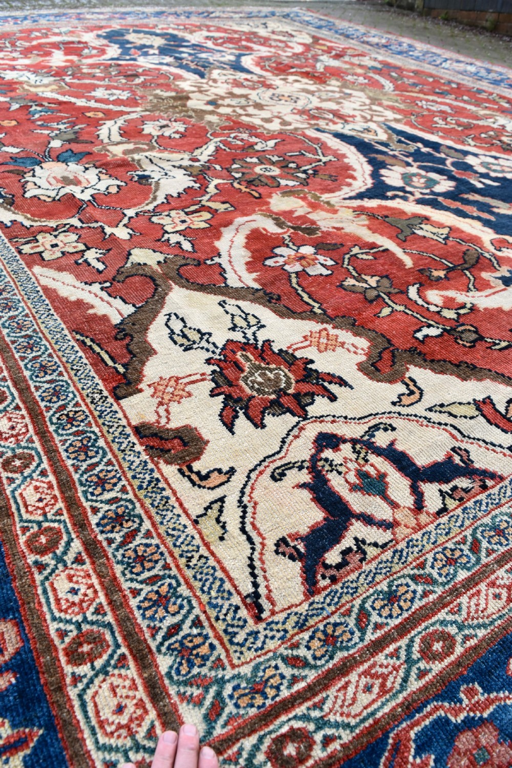 Large antique Ziegler Mahal wool carpet featuring a terracotta field with a central navy blue medallion and ornate floral borders. View XII