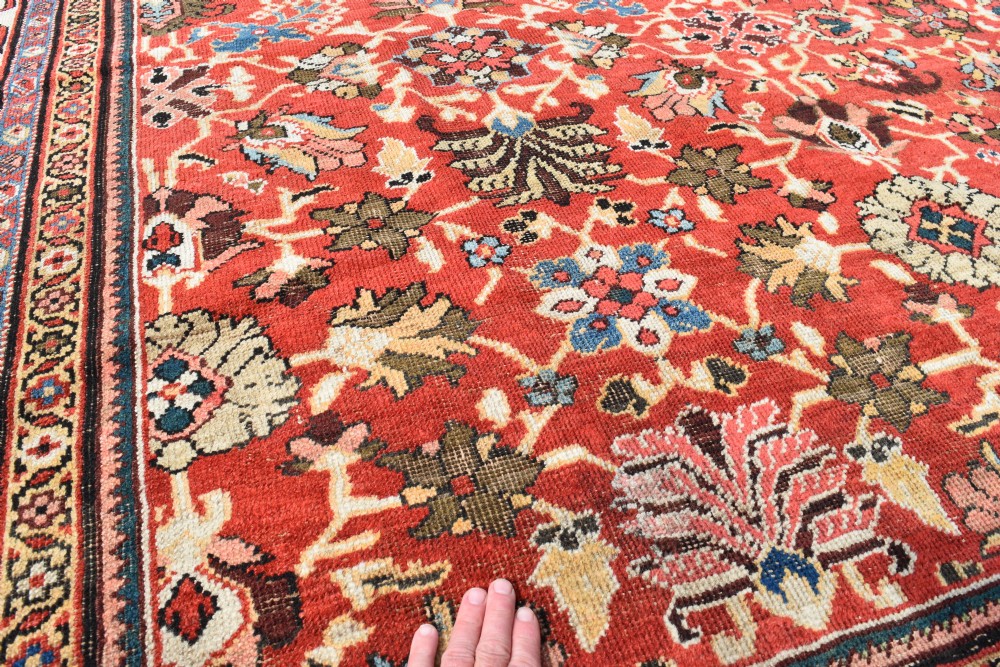 A large hand-knotted antique Persian Mahal carpet featuring a rust-red field filled with an intricate all-over floral pattern surrounded by a contrasting cream main border. View V