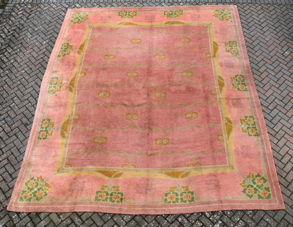 A large Arts and Crafts hand-knotted wool carpet in pink featuring mustard yellow and green stylised floral borders. View II