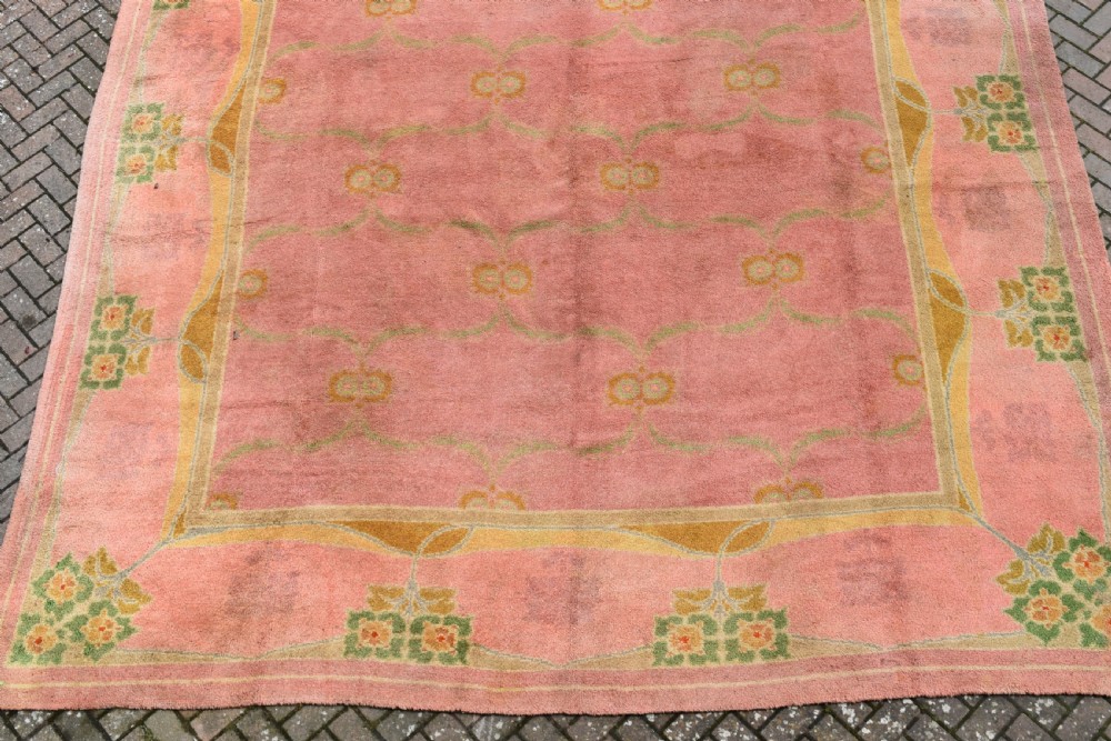 A large Arts and Crafts hand-knotted wool carpet in pink featuring mustard yellow and green stylised floral borders. View III