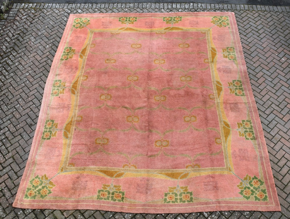A large Arts and Crafts hand-knotted wool carpet in pink featuring mustard yellow and green stylised floral borders. View V