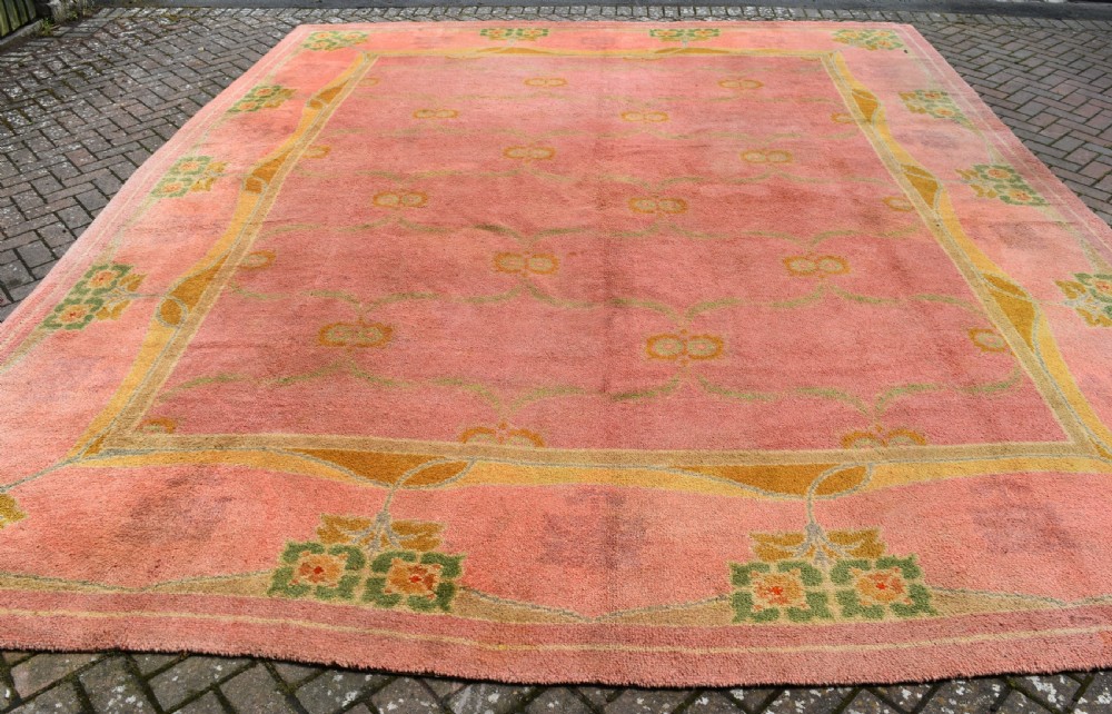 A large Arts and Crafts hand-knotted wool carpet in pink featuring mustard yellow and green stylised floral borders. View VI
