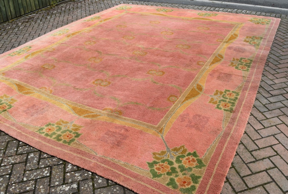 A large Arts and Crafts hand-knotted wool carpet in pink featuring mustard yellow and green stylised floral borders. View VII