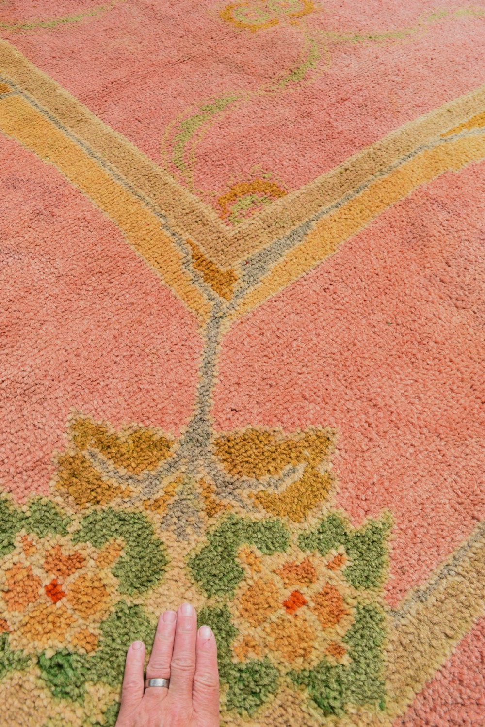 A large Arts and Crafts hand-knotted wool carpet in pink featuring mustard yellow and green stylised floral borders. View IX