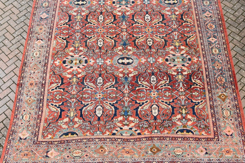 A large rectangular hand-knotted Persian Mahal carpet featuring a terracotta red ground with an all-over navy blue and beige floral palmette pattern framed by intricate borders. View II