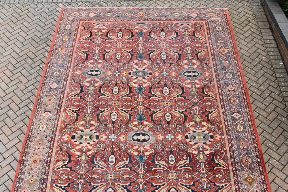 A large rectangular hand-knotted Persian Mahal carpet featuring a terracotta red ground with an all-over navy blue and beige floral palmette pattern framed by intricate borders. View III