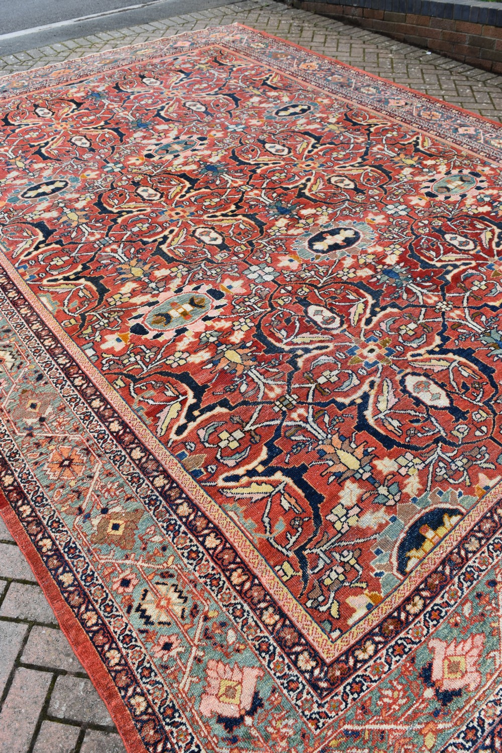 A large rectangular hand-knotted Persian Mahal carpet featuring a terracotta red ground with an all-over navy blue and beige floral palmette pattern framed by intricate borders. View V