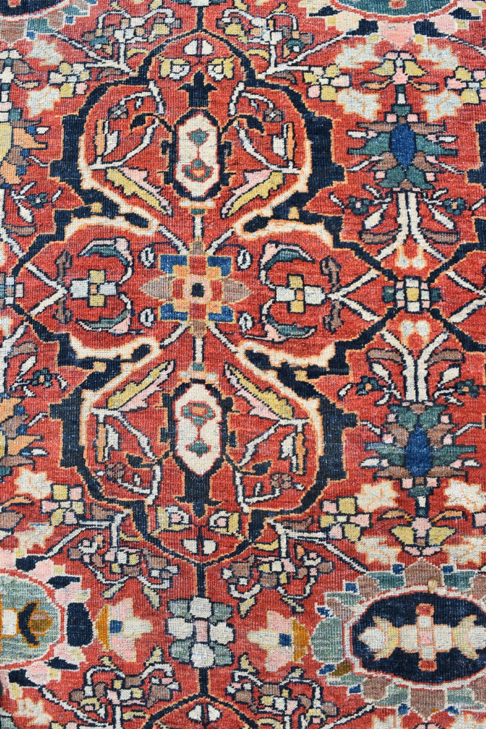 A large rectangular hand-knotted Persian Mahal carpet featuring a terracotta red ground with an all-over navy blue and beige floral palmette pattern framed by intricate borders. View VI