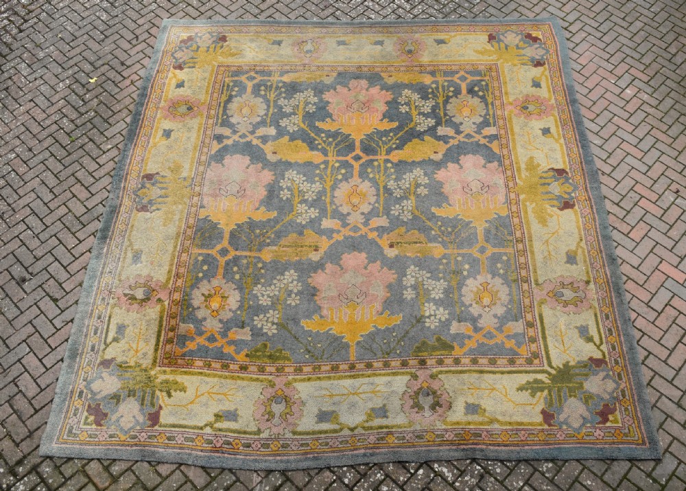 A large hand-knotted Gavin Morton Donegal wool carpet featuring stylised floral motifs in pink, ochre, and green across a slate blue field. View II