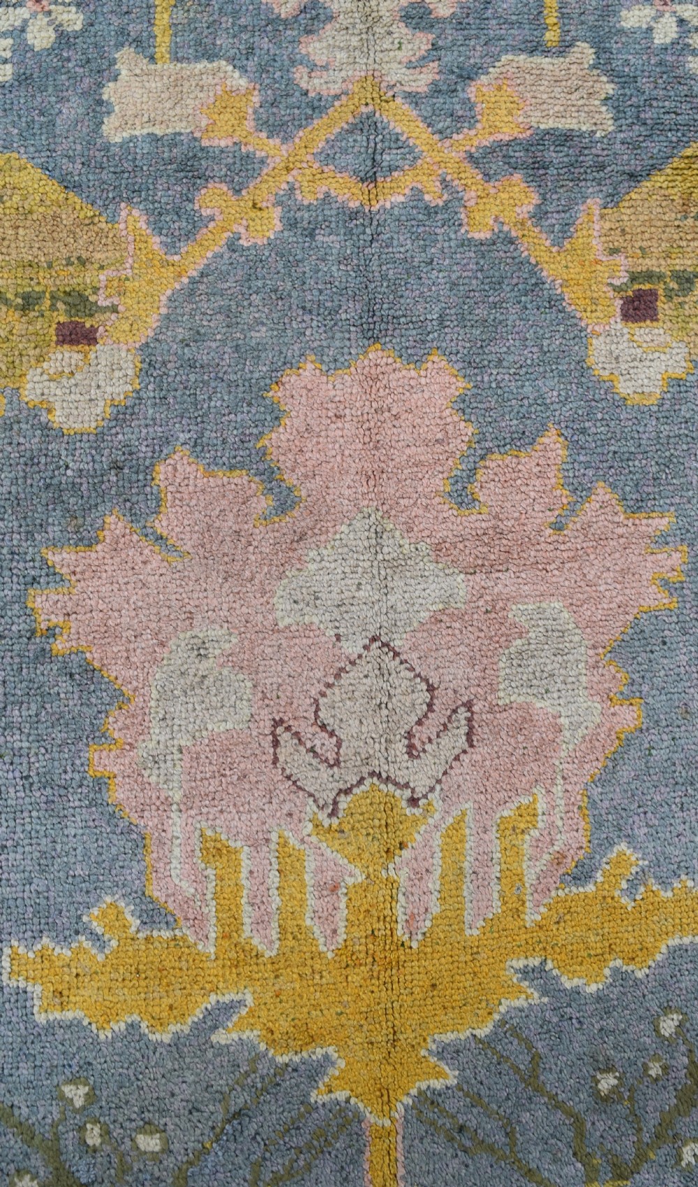 A large hand-knotted Gavin Morton Donegal wool carpet featuring stylised floral motifs in pink, ochre, and green across a slate blue field. View III