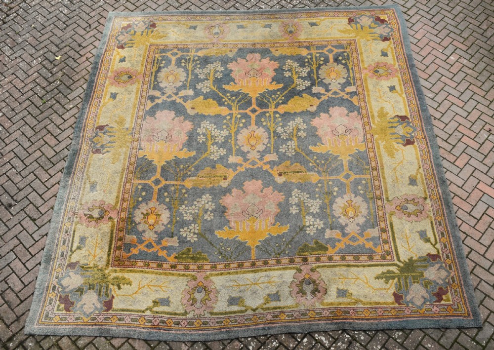 A large hand-knotted Gavin Morton Donegal wool carpet featuring stylised floral motifs in pink, ochre, and green across a slate blue field. View VII
