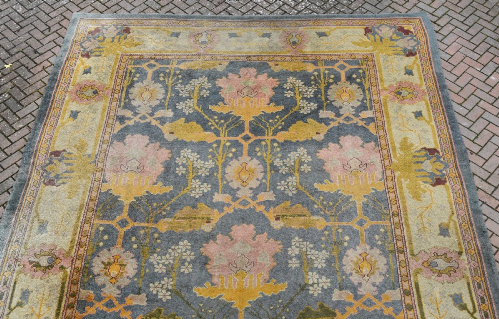 A large hand-knotted Gavin Morton Donegal wool carpet featuring stylised floral motifs in pink, ochre, and green across a slate blue field. View XIV